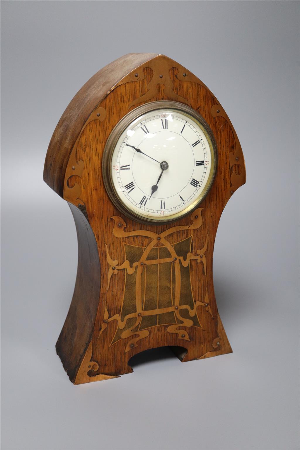 An Art Nouveau inlaid oak mantel clock, convex dial and French movement, case inlaid with copper strapwork, 28cm